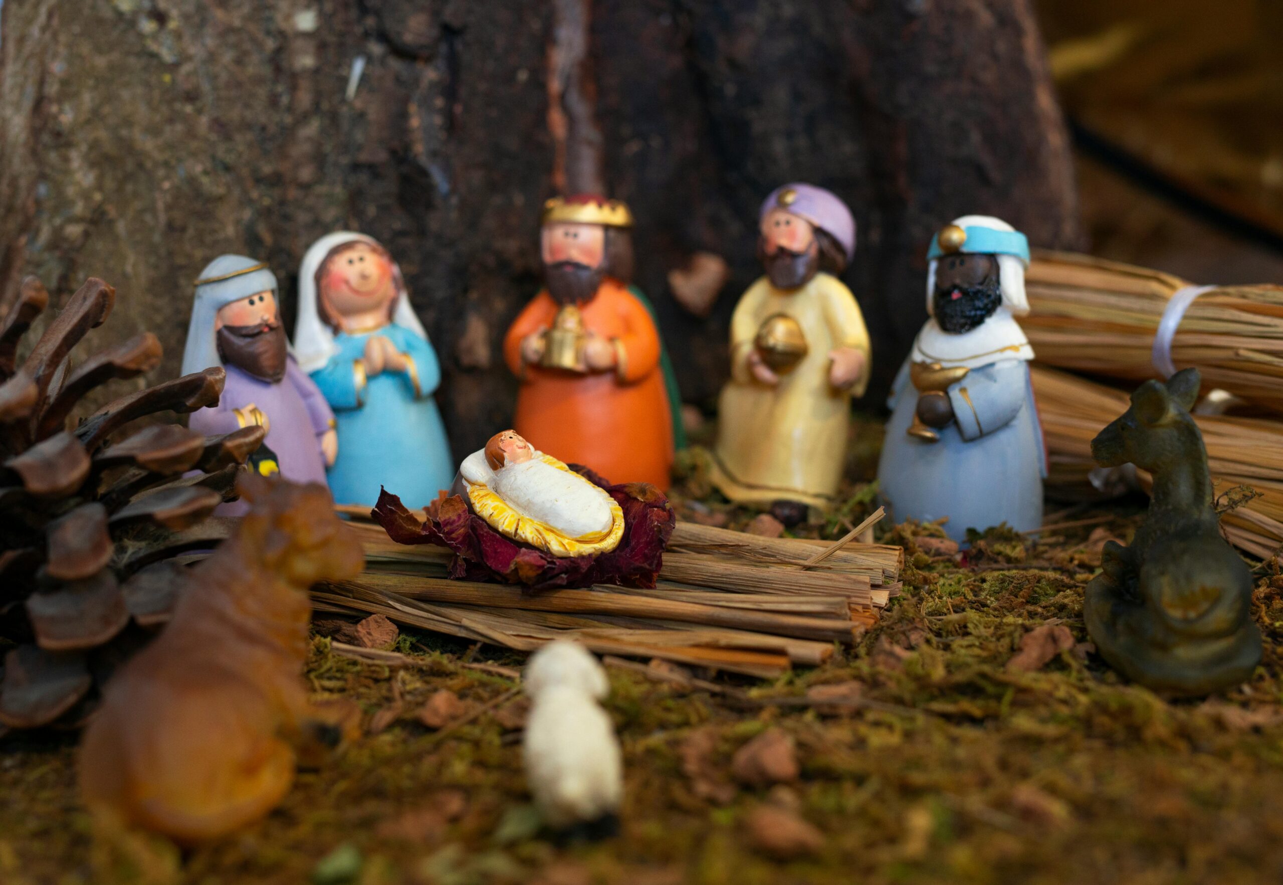 Child touching a Nativity scene toy, learning the Christmas story